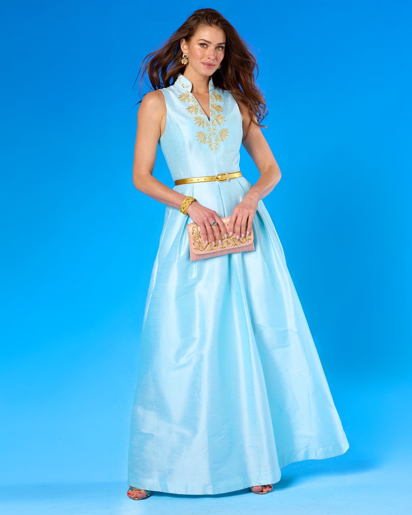 Woman in a light blue dress with gold accents against a blue background