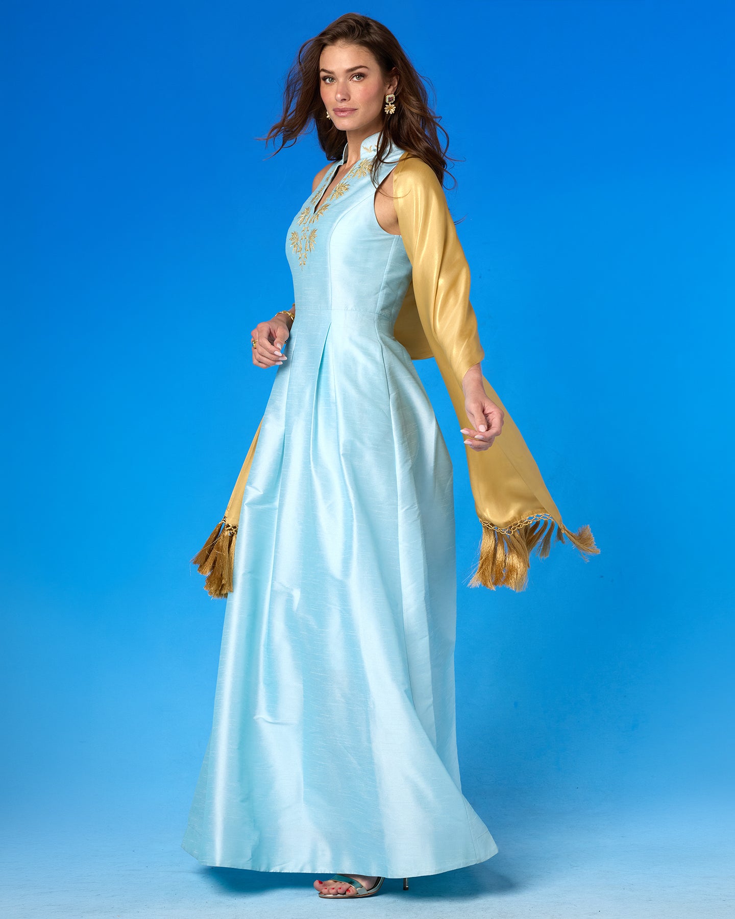 The Arabella Fringe Shawl in Pale Gold Shimmer worn with the Celestine Gown in Pastel Blue and Gold Palm Embroidery