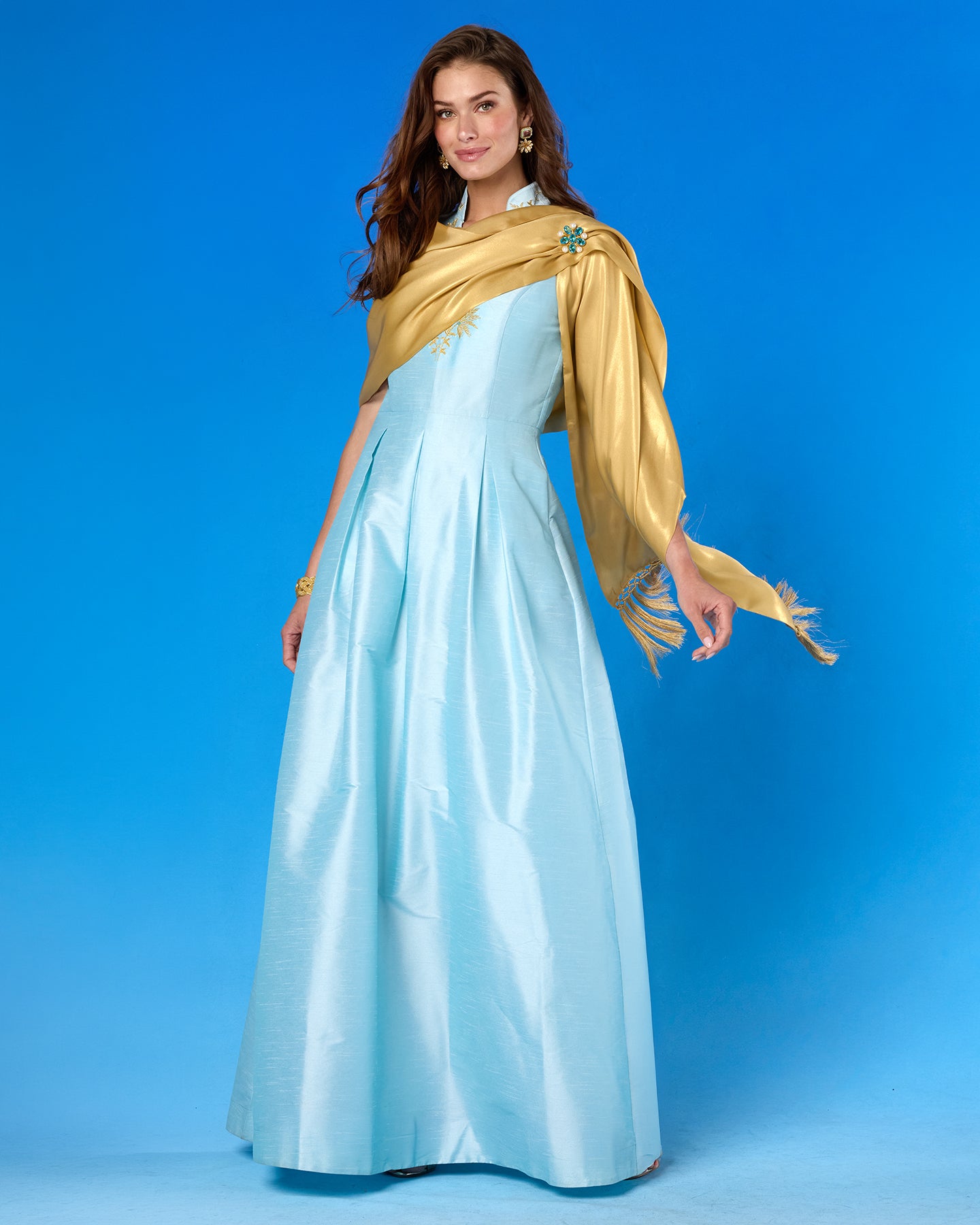 Woman wearing a light blue saree with a gold blouse against a blue background