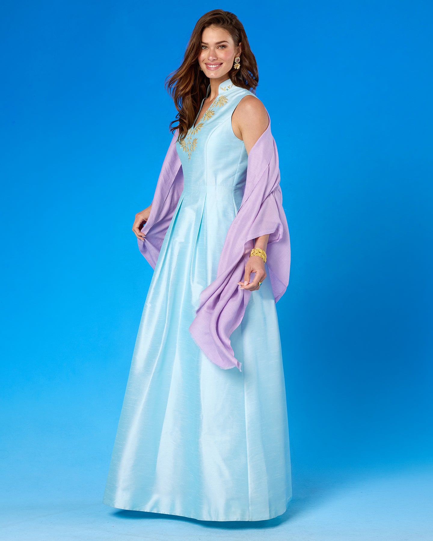 Woman wearing a light blue dress with a purple shawl against a blue background