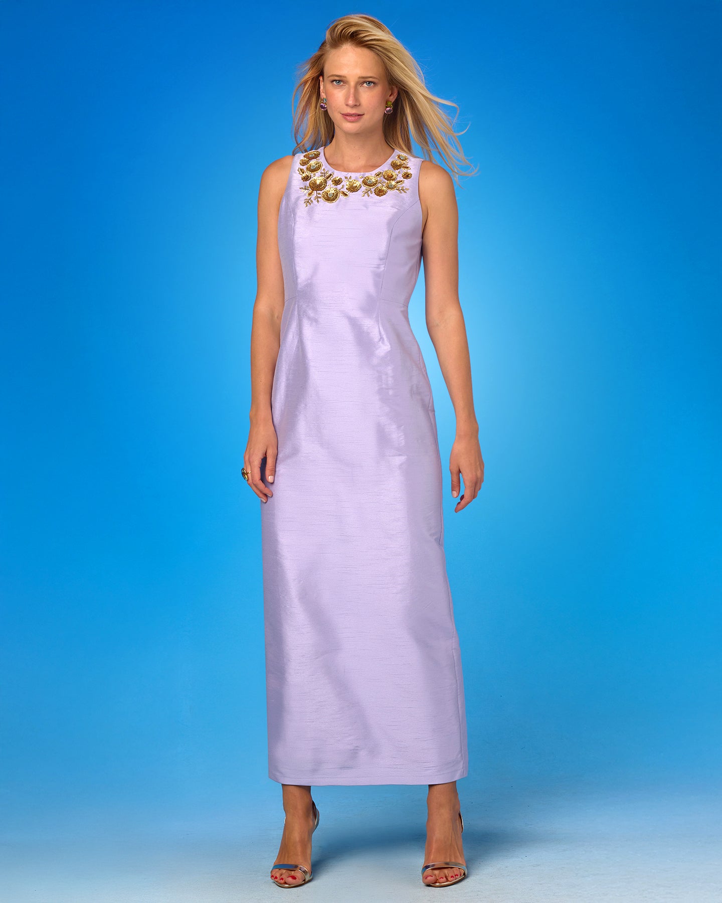 Woman wearing a light purple dress with gold embellishments on a blue background