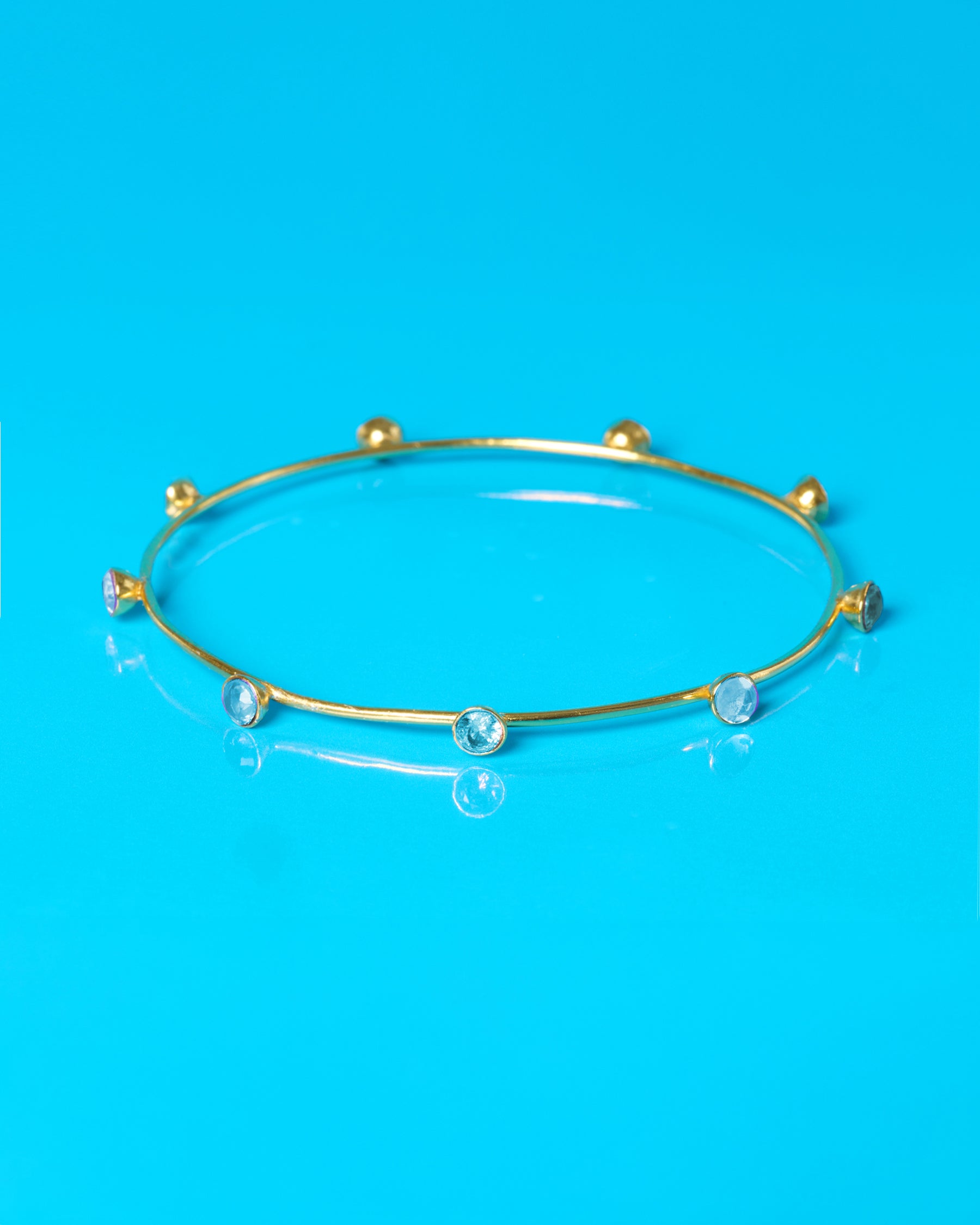 Gold bracelet with blue stones on a blue background