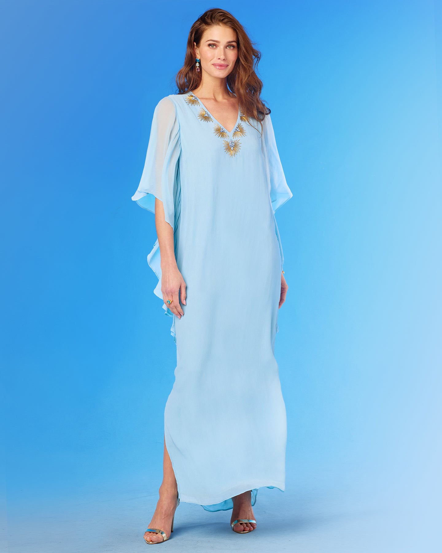 Woman wearing a light blue dress with floral embellishments on a blue background