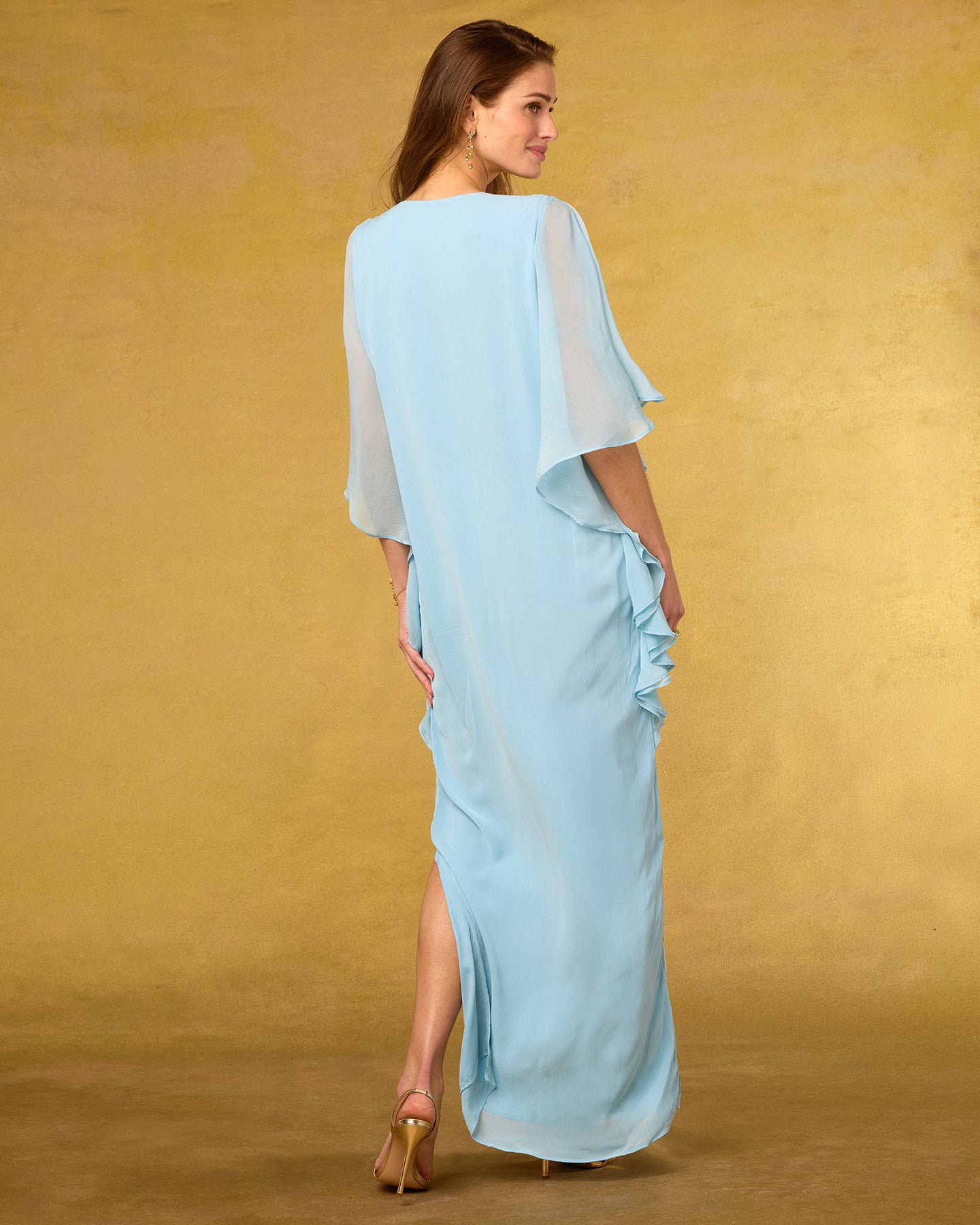 Woman wearing a light blue dress with ruffled sleeves against a mustard yellow background