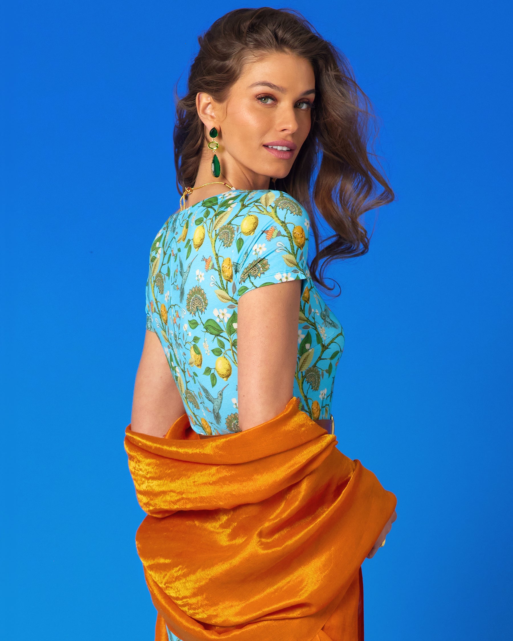 Josephine Reversible Pashmina Shawl in Gold Shimmer Coral Orange worn with the Flora Long Stretch Dress in Turquoise Hummingbird Print-Back View