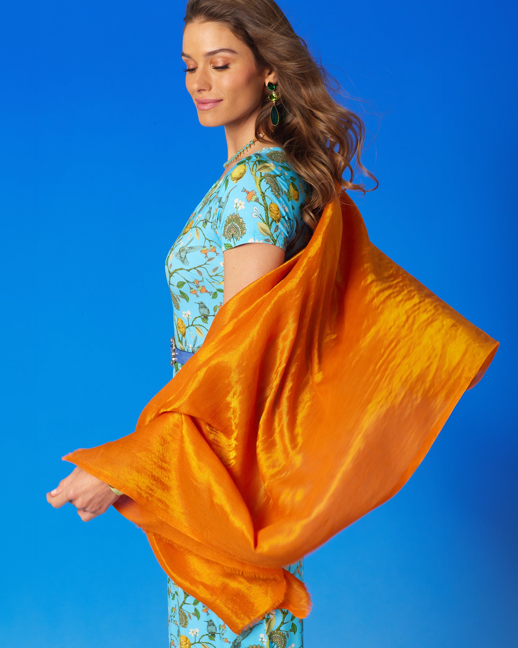 Model waving the Josephine Reversible Pashmina Shawl in Gold Shimmer Coral Orange in the wind