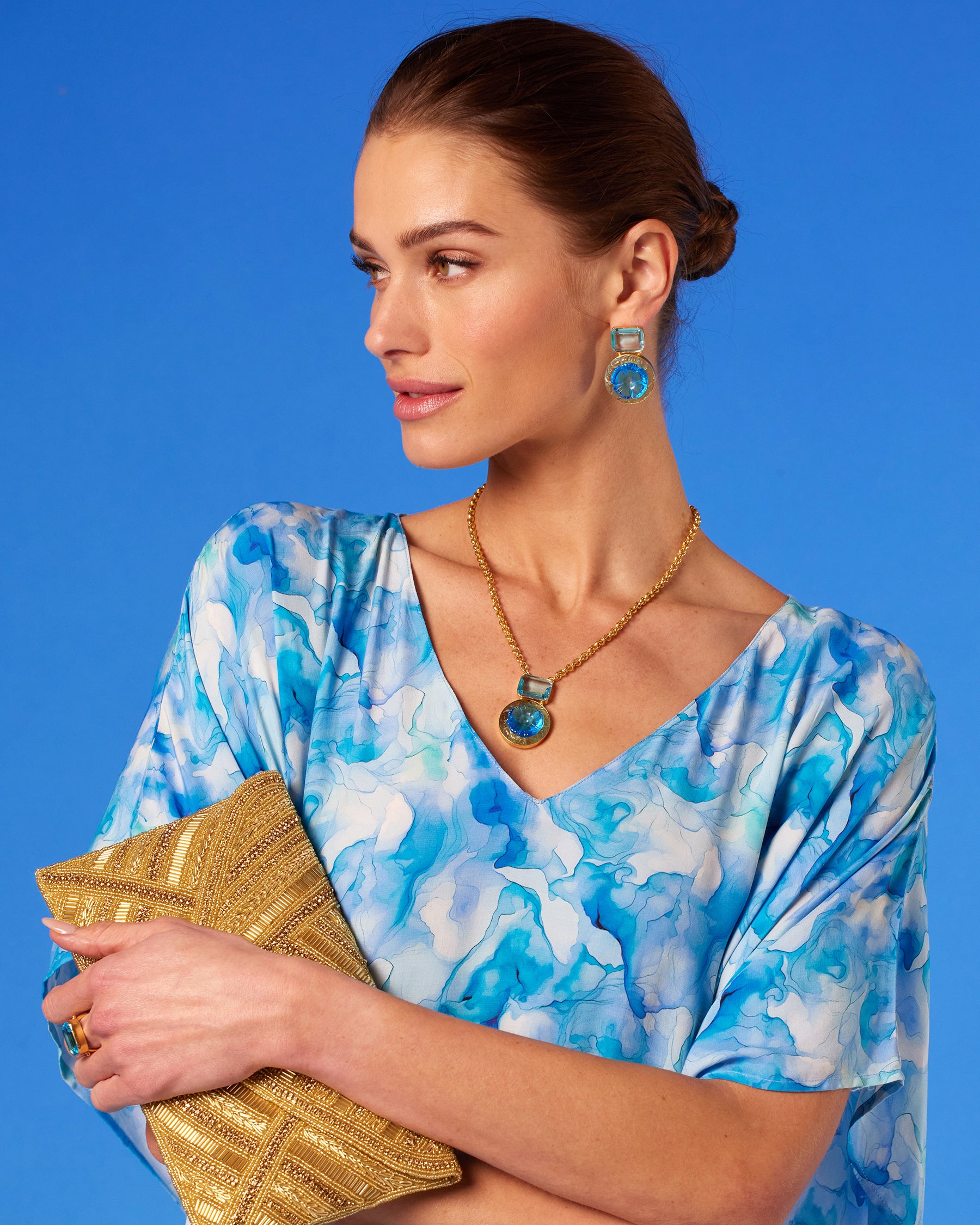 Isla Kaftan in Sea Swirl Blues closeup holding the Betty Gold Beaded Clutch