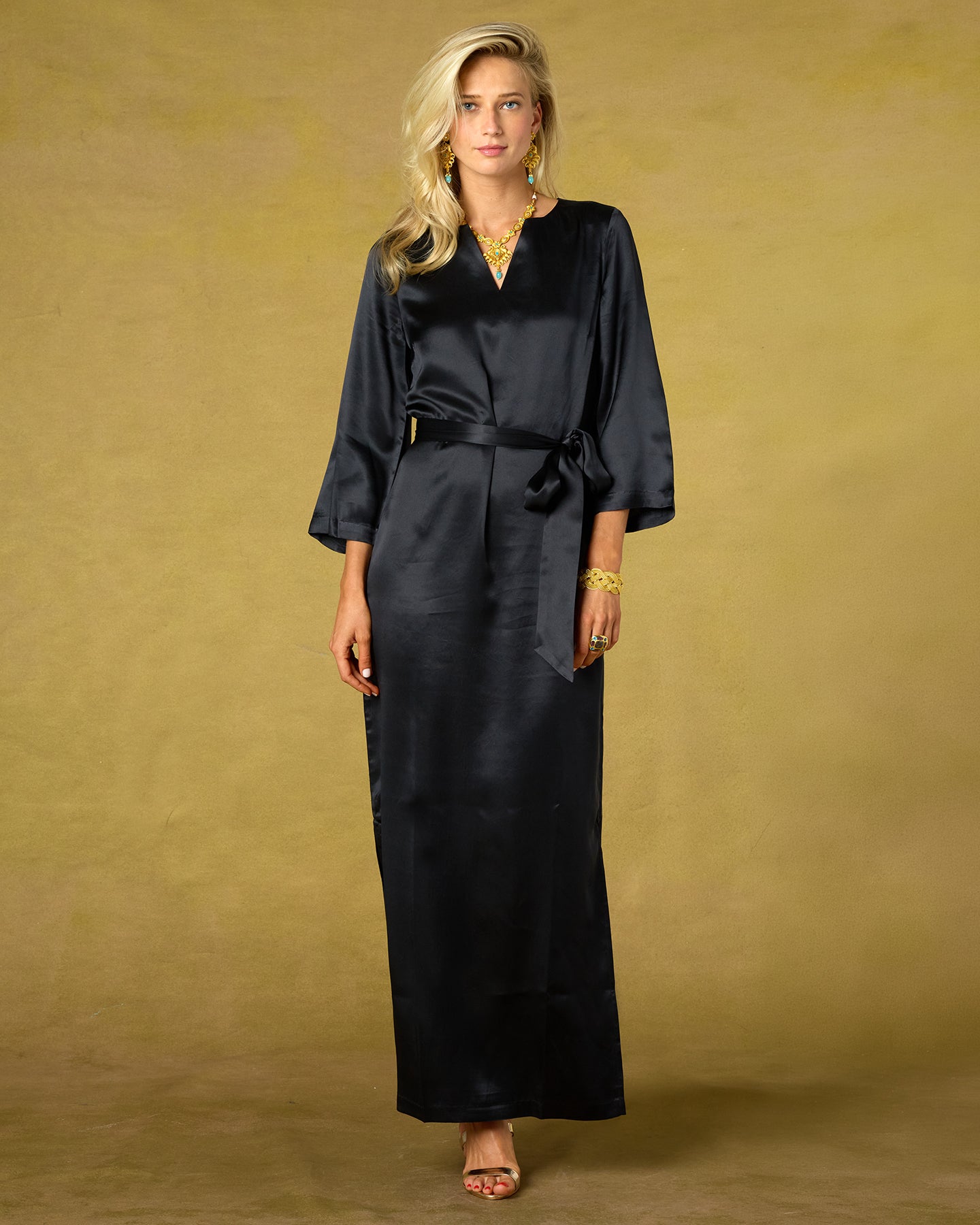Woman wearing a black dress with a belt against a beige background