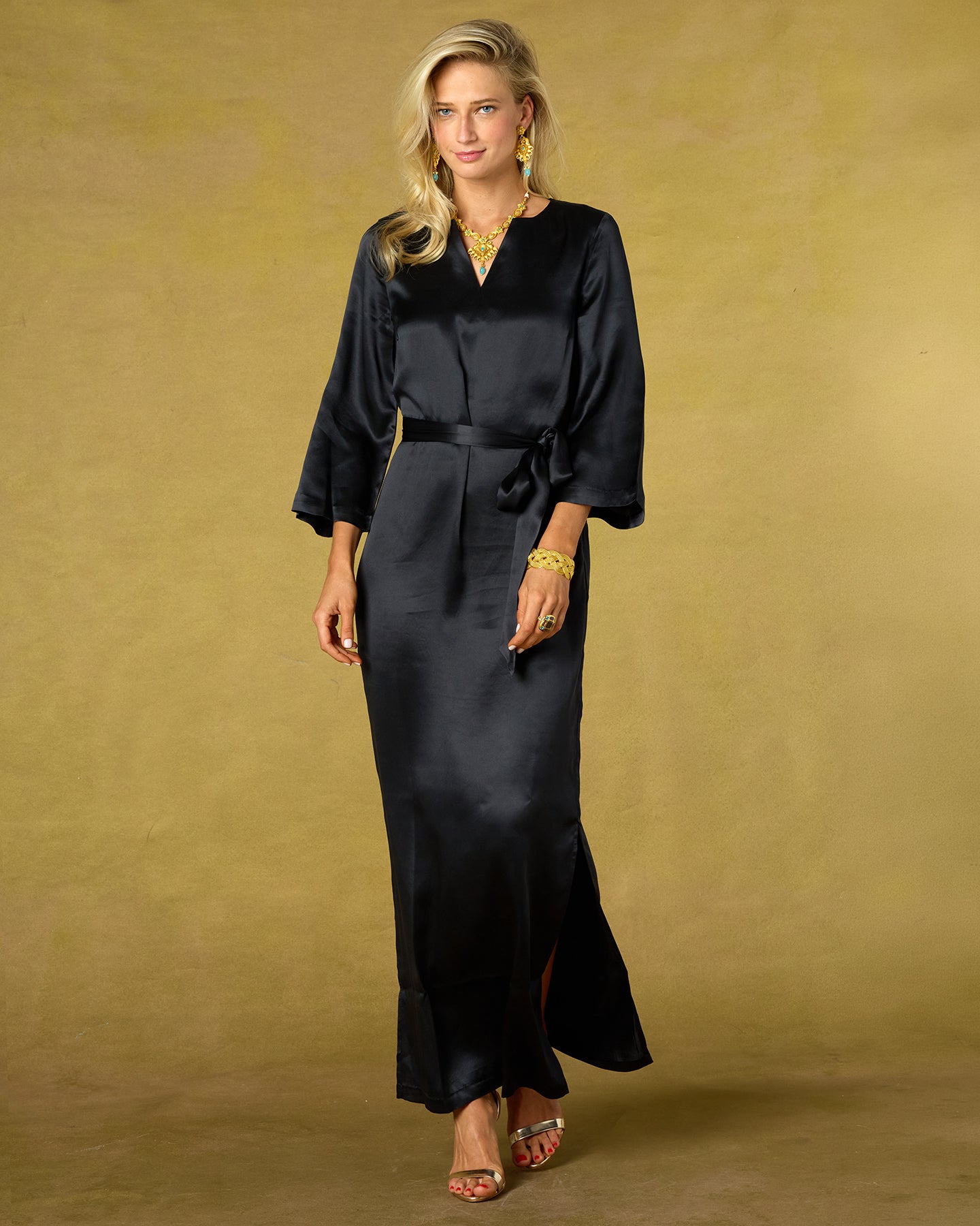 Woman wearing a black dress with a belt against a beige background
