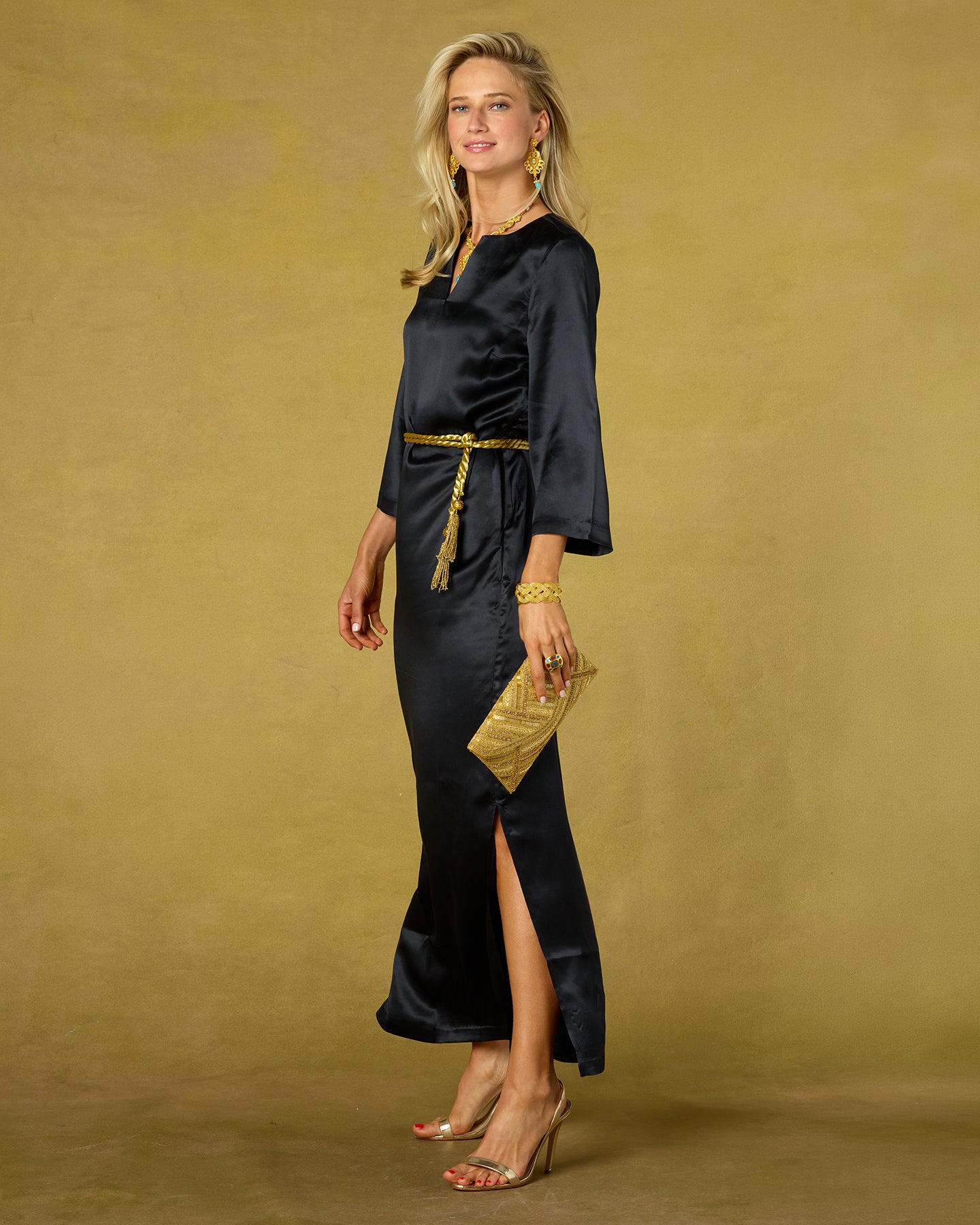 Woman in a black dress with gold accents on a beige background