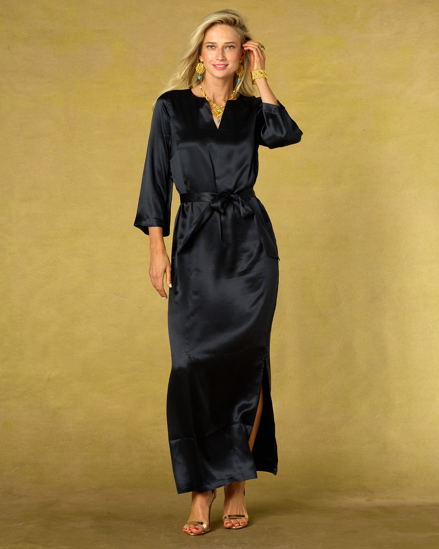 Woman wearing a black satin dress against a gold background