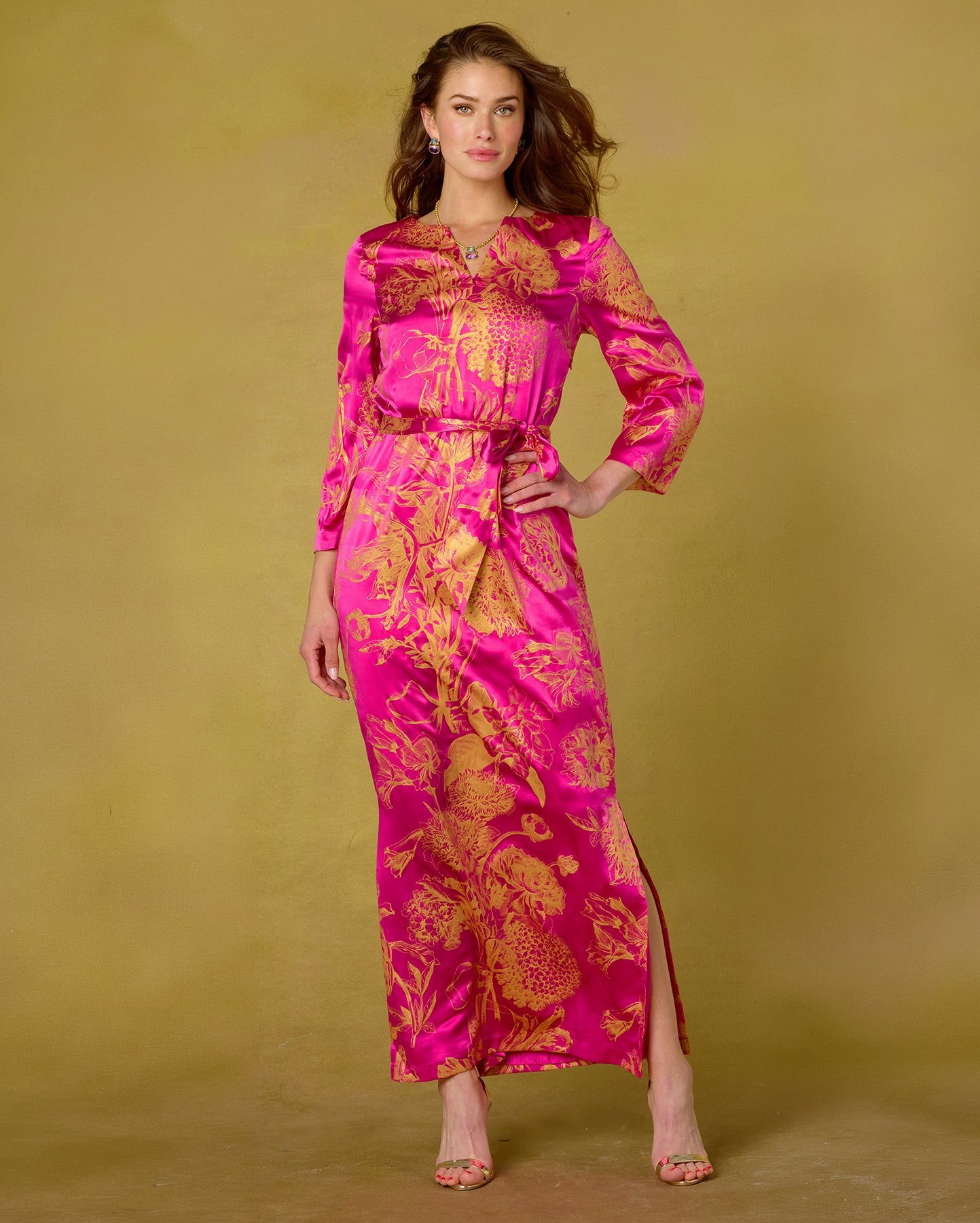 Woman wearing a pink and gold floral dress against a beige background