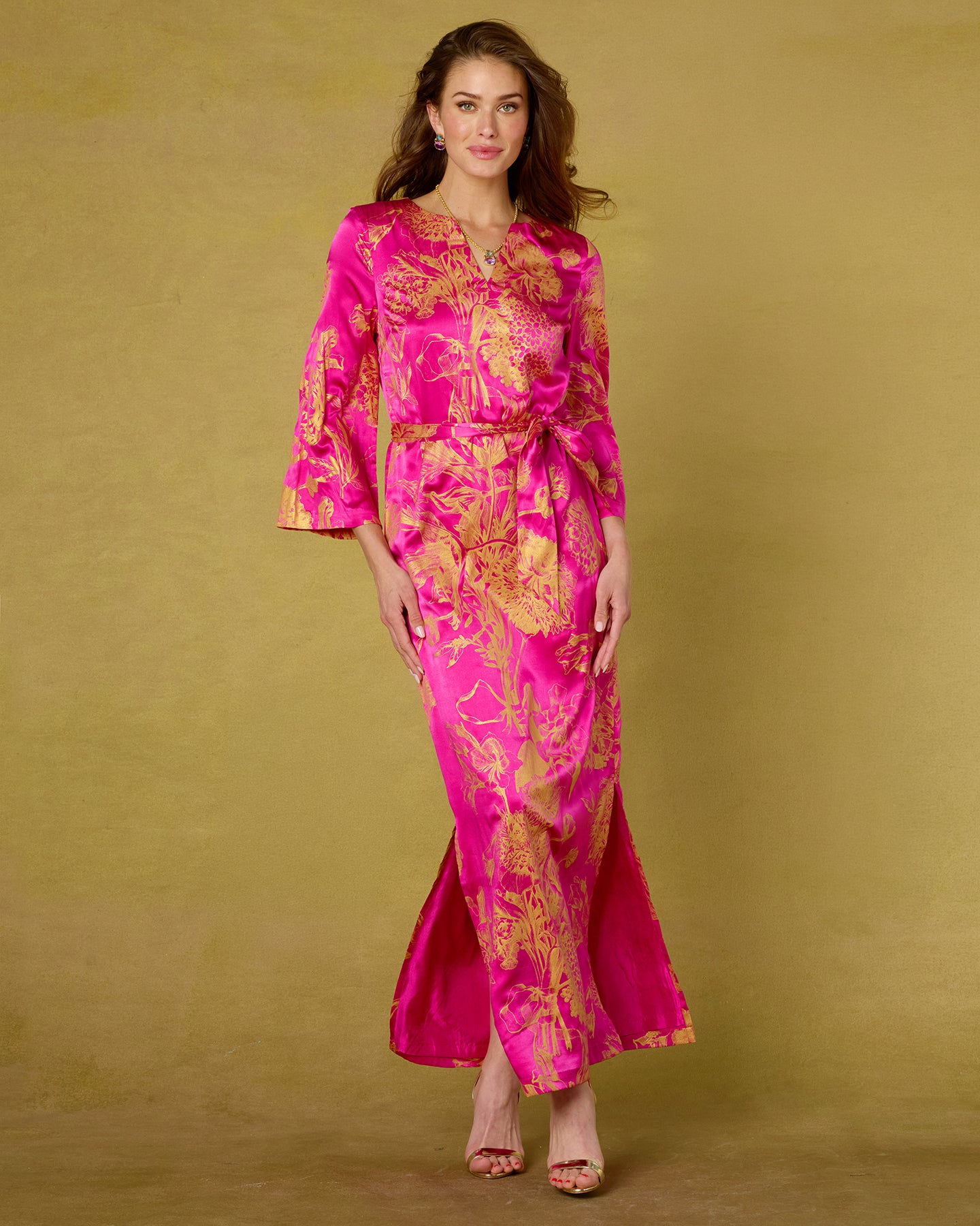 Woman wearing a pink and gold floral dress against a beige background