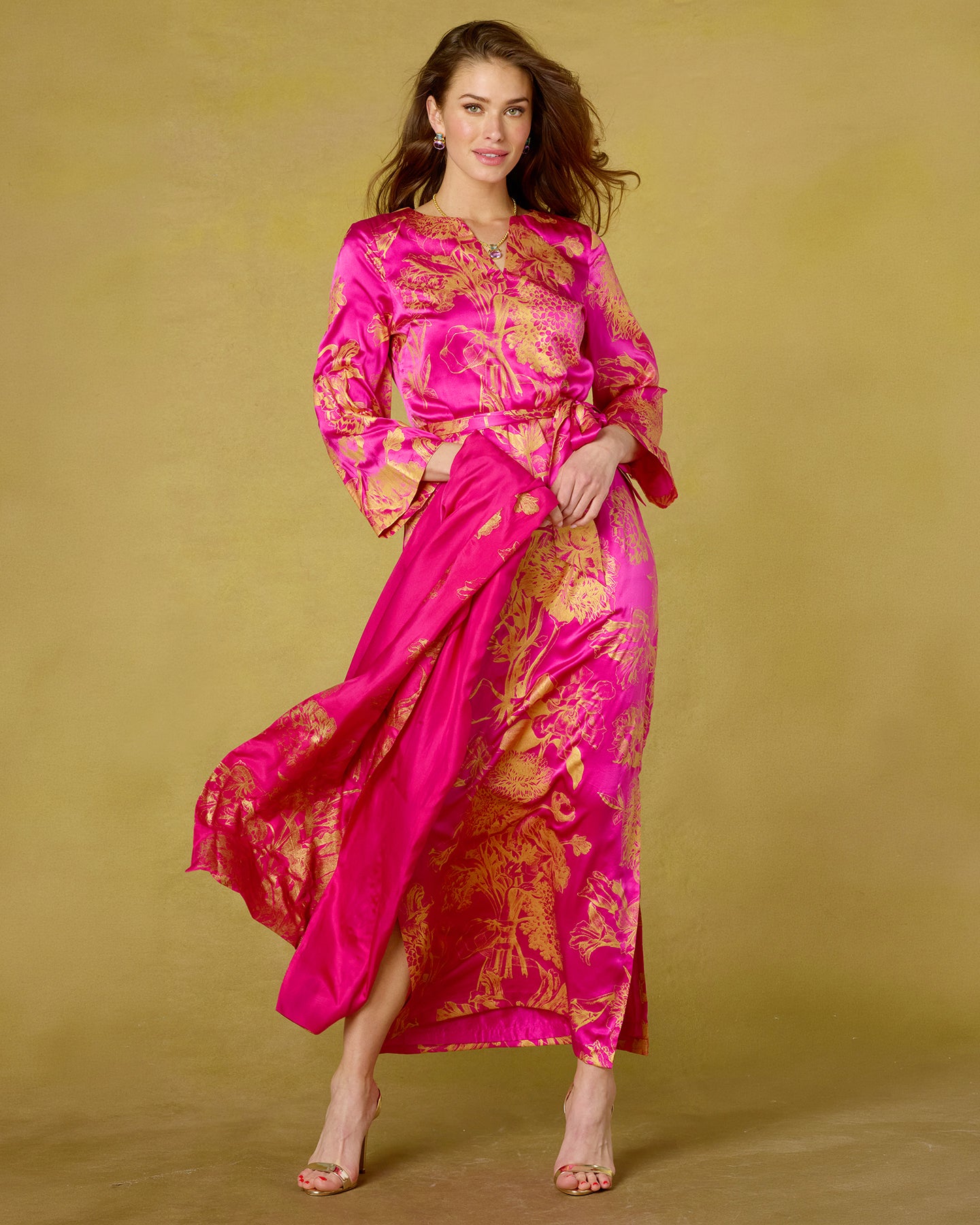 Woman wearing a pink and gold traditional outfit on a beige background