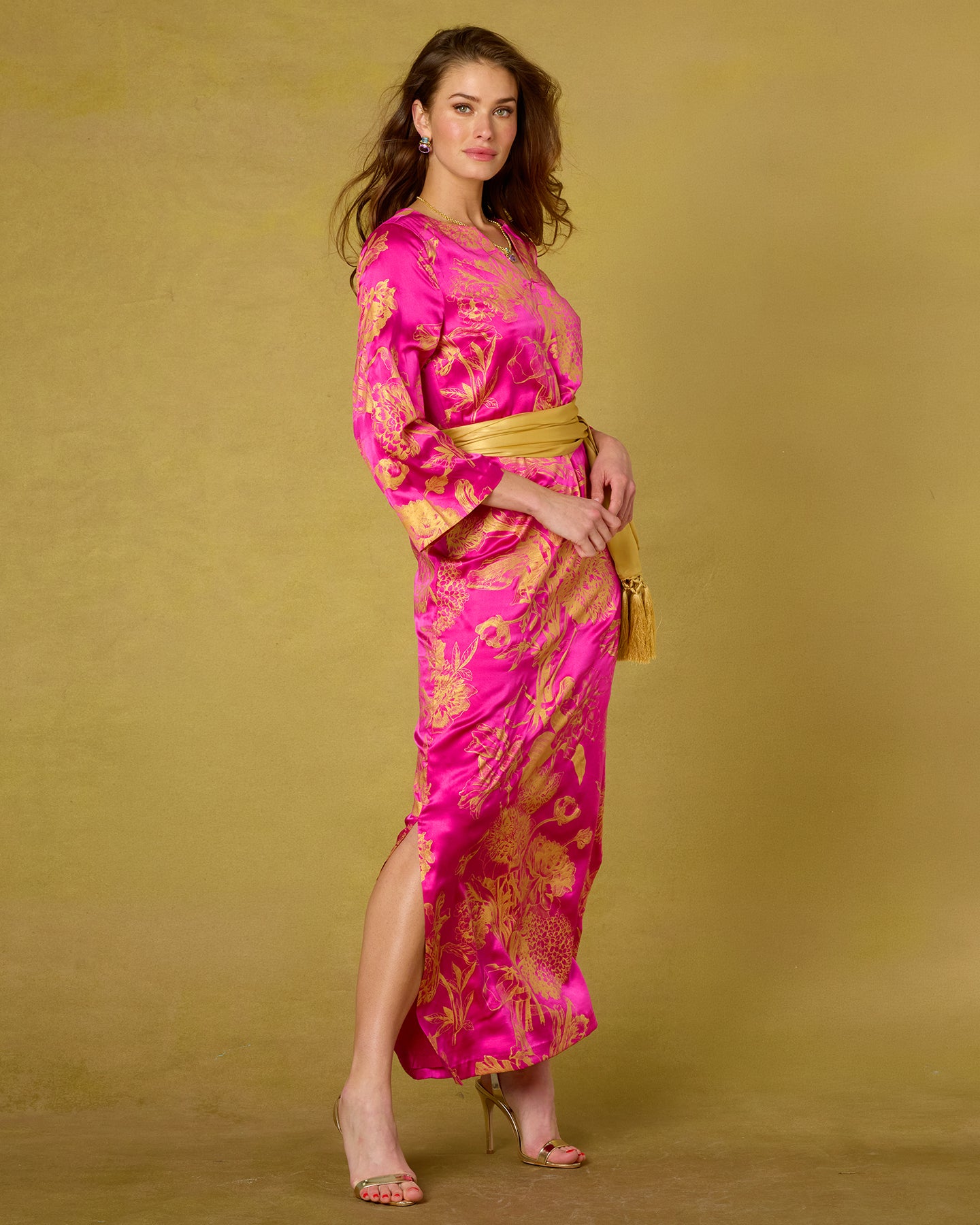 Woman wearing a pink and gold dress against a beige background