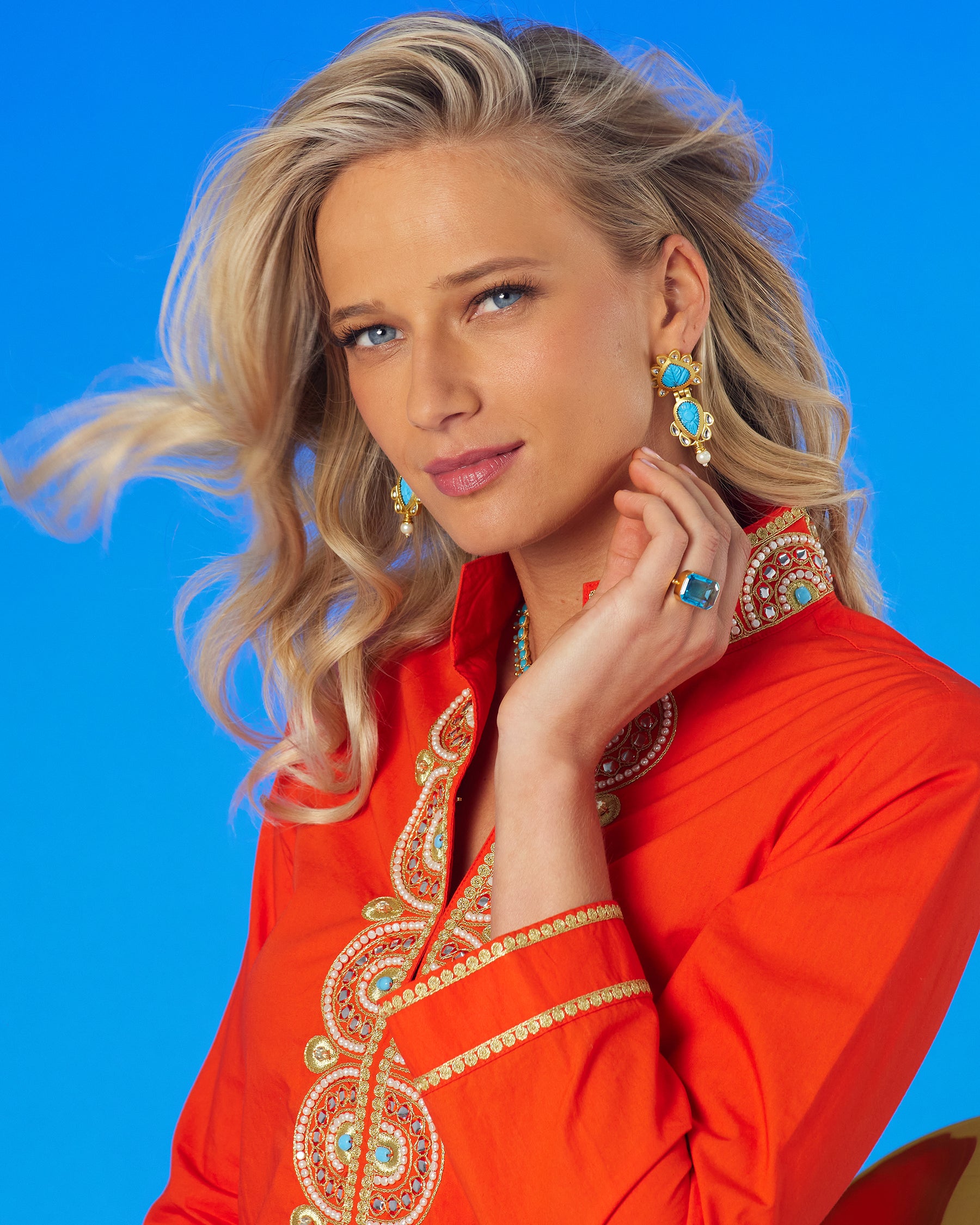 Portrait of model wearing Noor Orange Tunic with Gold Embellishment and hand to ear