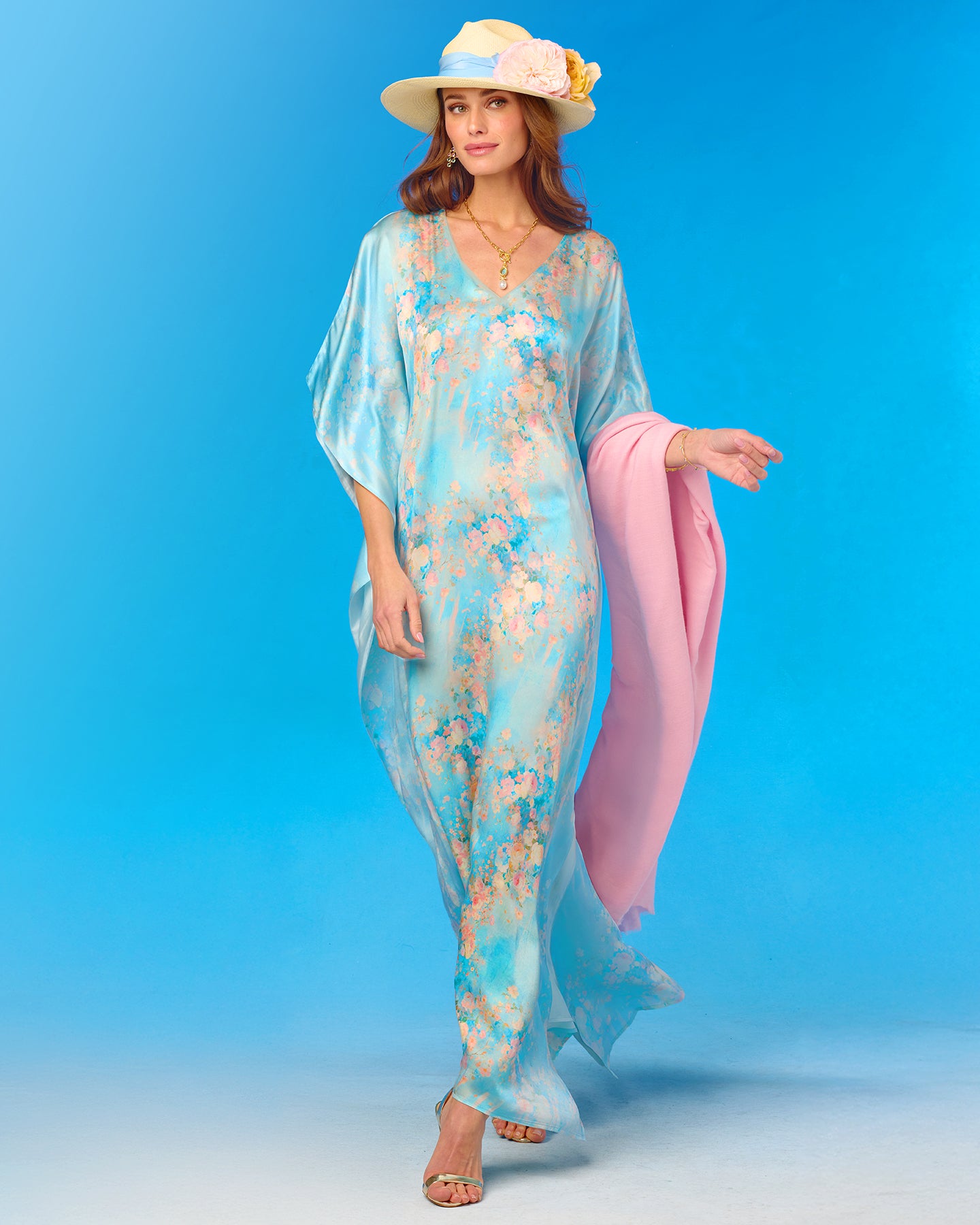 Woman wearing a light blue floral dress with pink pants against a blue background