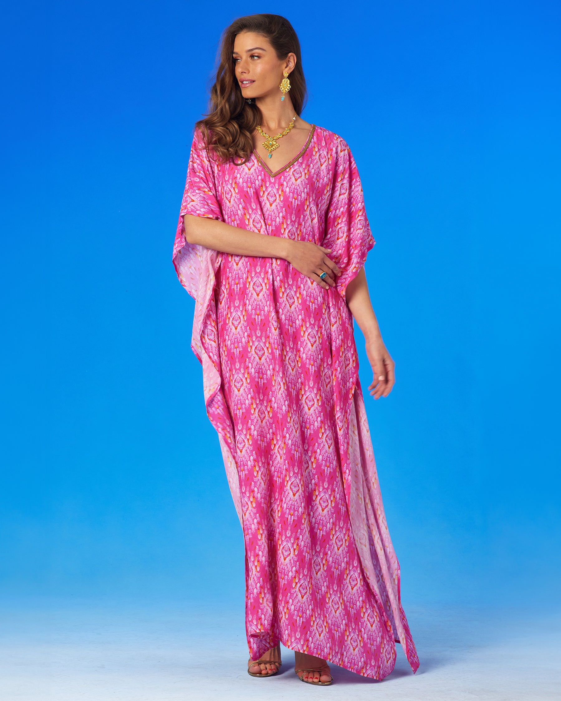 Orchidea Kaftan in Fuchsia Pink Ikat and Gold Beaded Trim full frontal view, woman looking off to the side