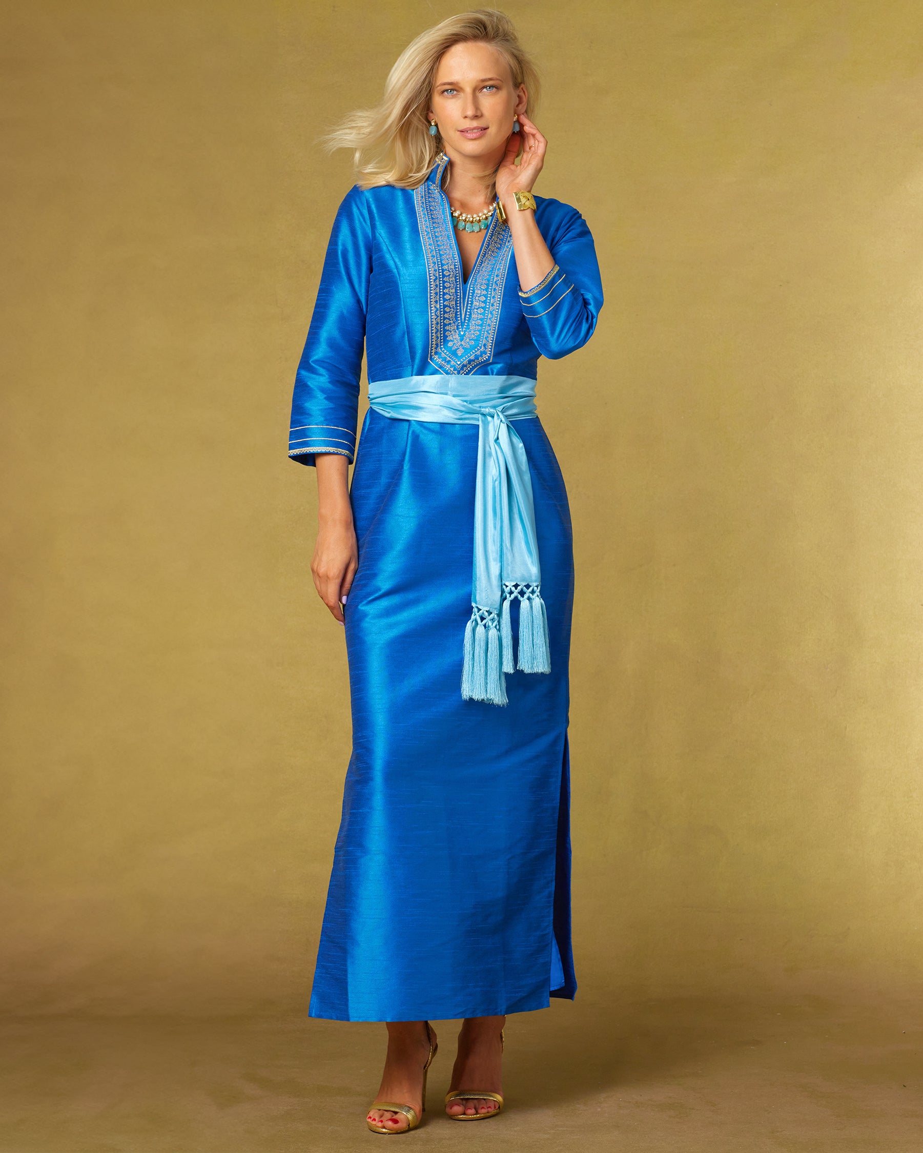 Regine Long Tunic Dress in Royal Blue and Gold Embroidery with the waist cinched with the Cosima Turquoise Sash Belt-Front View with arm up