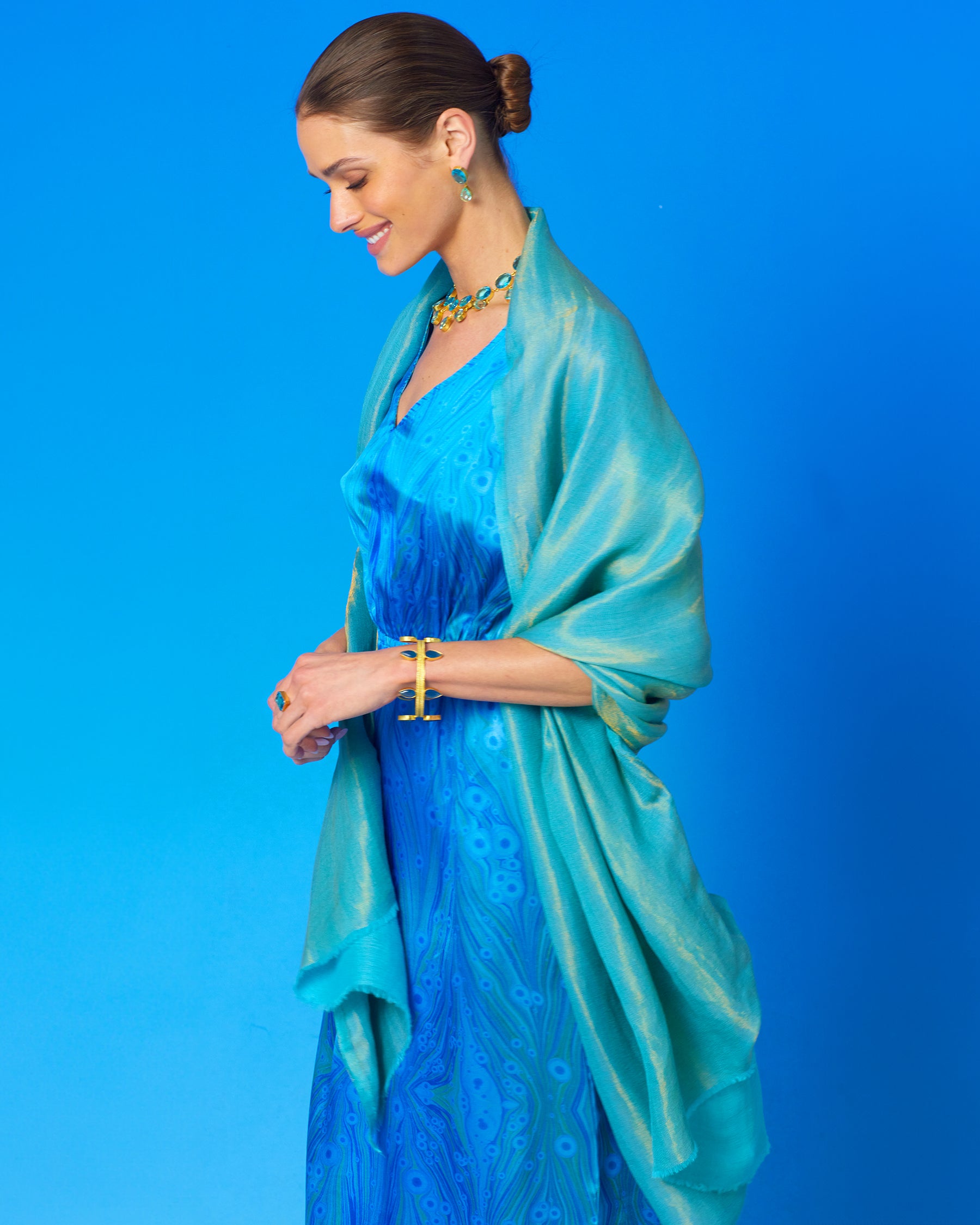 Calliope Long Silk Dress in Sea Nymph Blues with the Josephine Pashmina Shawl in Turquoise Gold Shimmer draped over the shoulders side view smiling