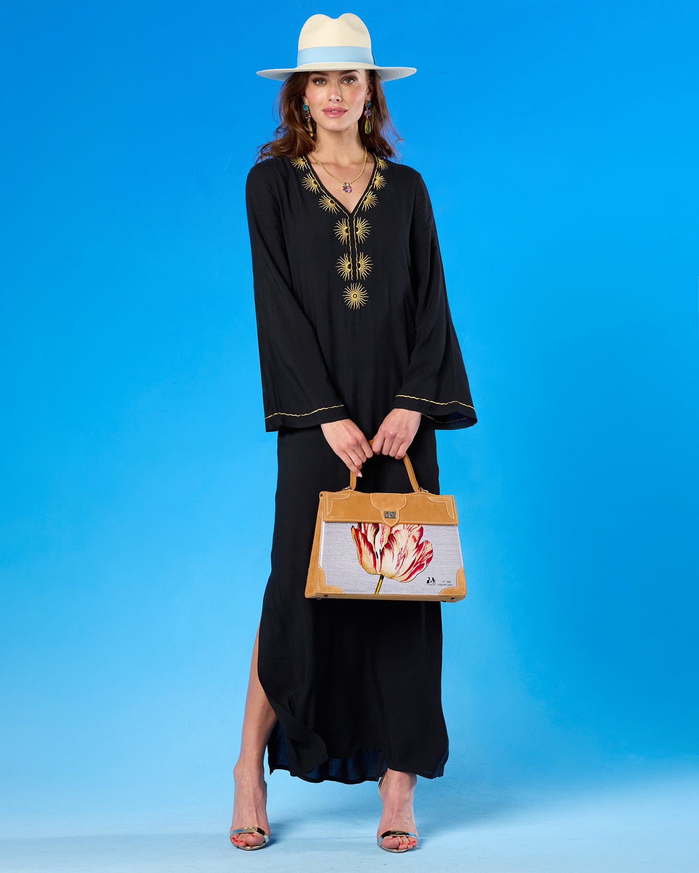 Woman in a black dress holding a handbag with a blue background