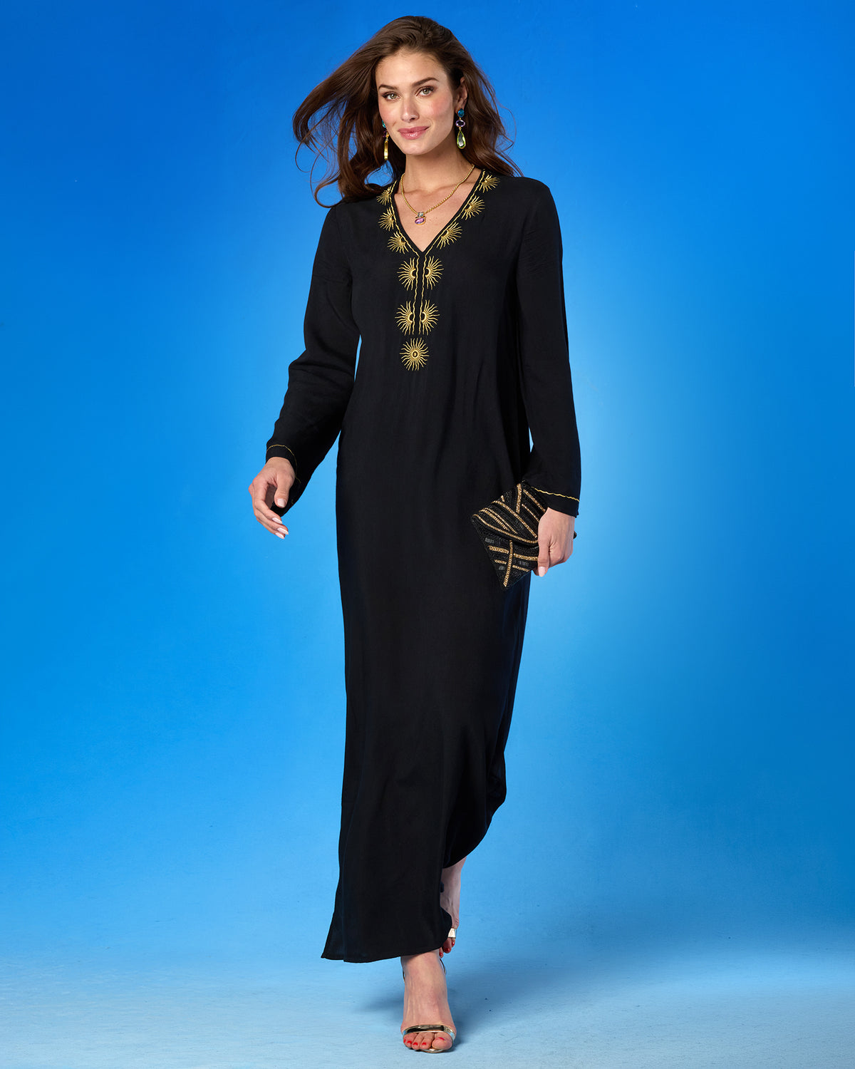 Woman wearing a black dress with gold embroidery on a blue background