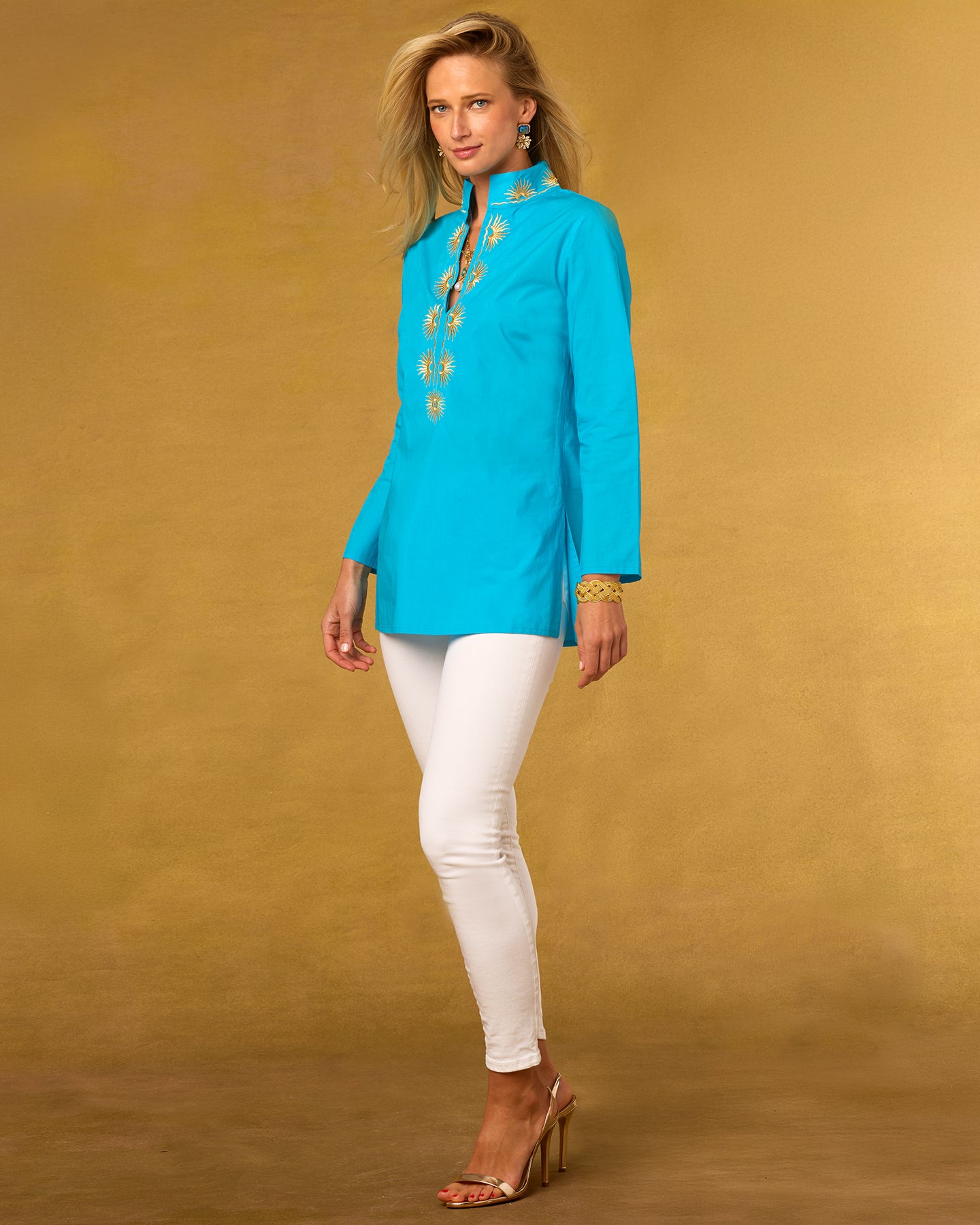 Woman wearing a turquoise blouse with white pants on a brown background