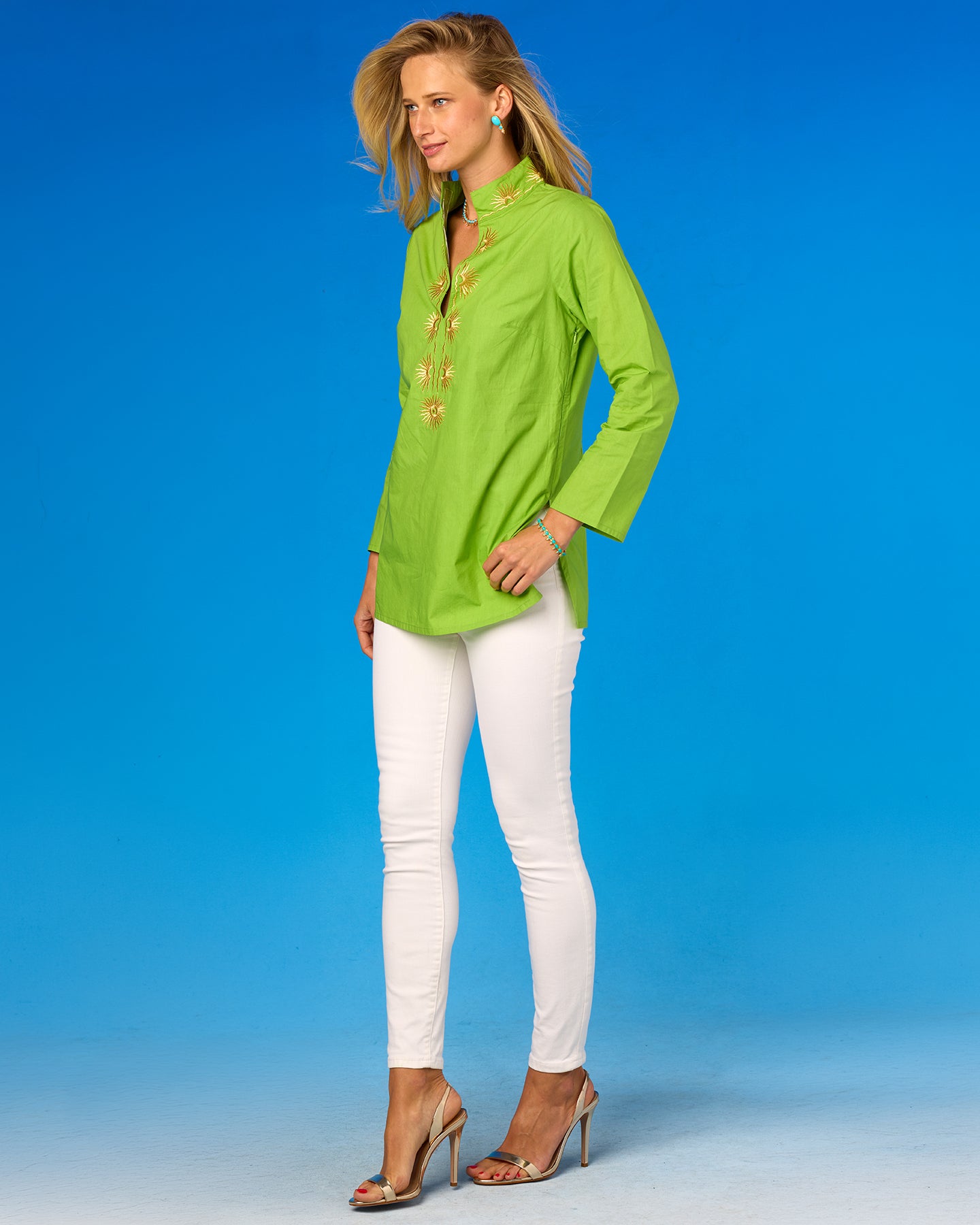 Woman wearing a bright green shirt and white pants against a blue background