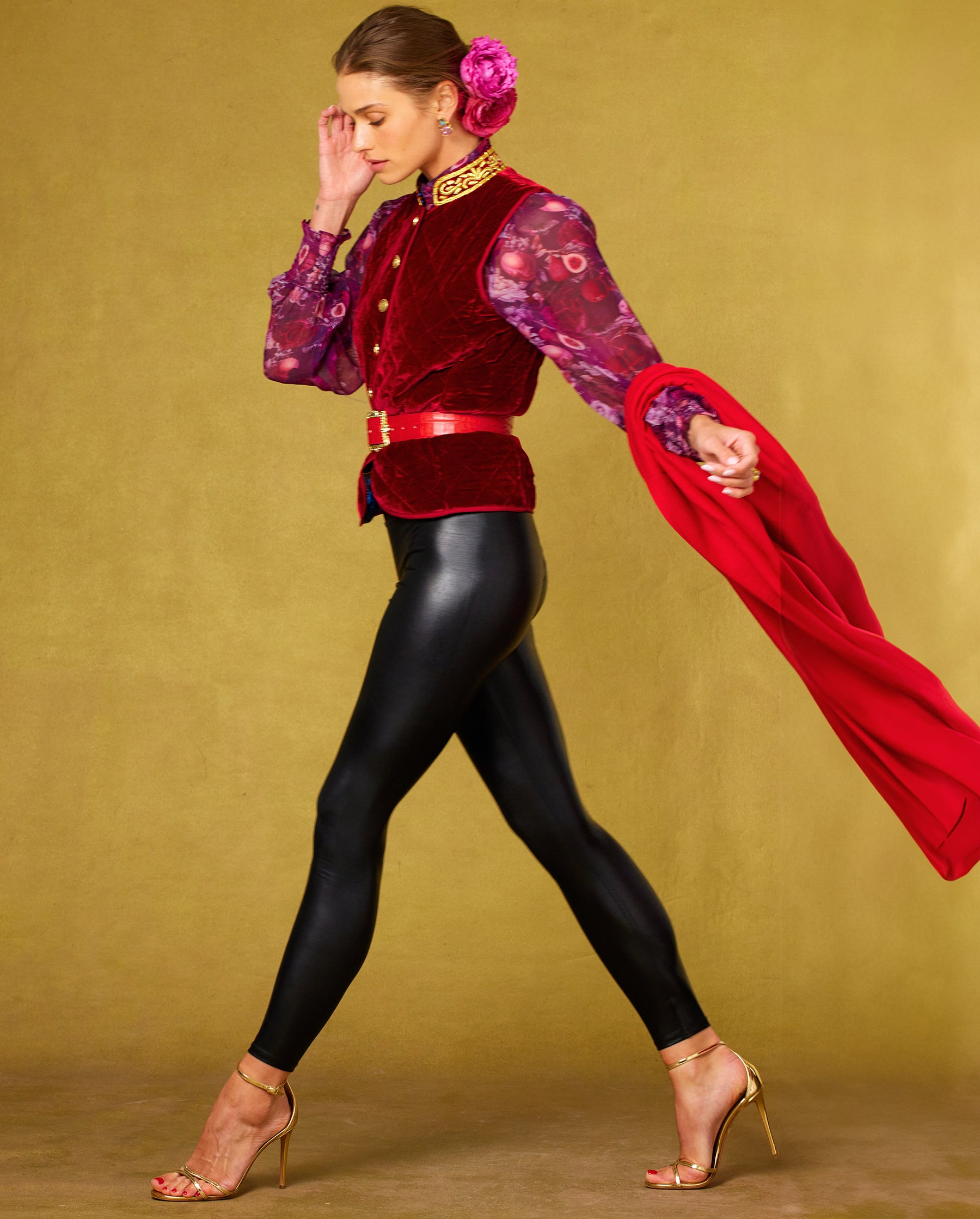 Side view walking of the Roxana Lacquer Black Leggings worn with the Bentley Quilted Vest in Crimson Red Silk Blend Velvet and Gold Embellishment and Tess Crinkle Chiffon Blouse in Opulent Harvest